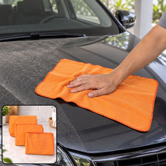 A hand wipes a dusty black car hood with an unfolded orange duster cloth, with two folded cloths inset.
