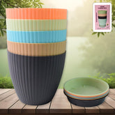 Set of 5 round plastic flower pots with trays on wooden surface