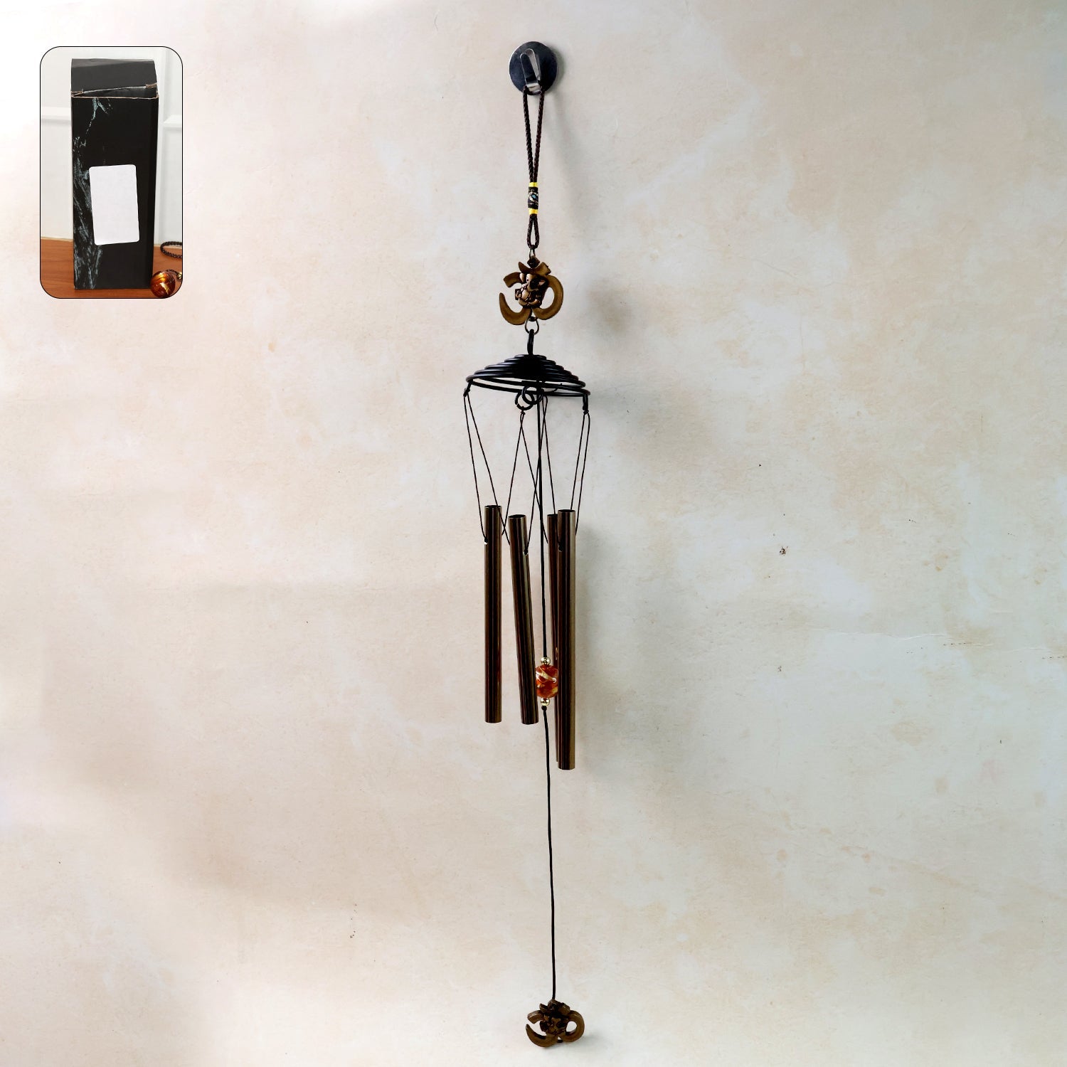 Metal wind chime with Om symbol hanging outdoors