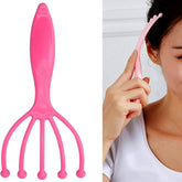 Handheld scalp massager with metal balls on wooden surface