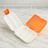 Orange dual-sided pill organizer box, closed