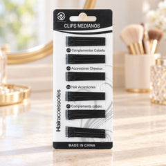 A black and white package of U-shaped hair pins sits on a vanity with a mirror and makeup brushes.