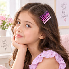 A young girl with long brown hair smiles, wearing multiple pink and purple glitter bobby pins on the side of her head.
