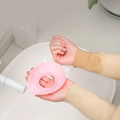 Person wearing pink silicone wrist bands while washing face