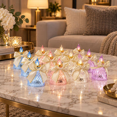 Twelve glowing faceted LED candles with cream bows and gold trim illuminate a light marble table in a living room setting.