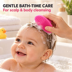 A smiling baby in a bubble bath has their hair gently brushed with a pink silicone scrubber by an adult's hand.