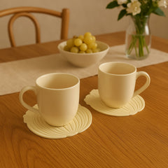 Lifestyle shot of two leaf-design silicone coasters on a table