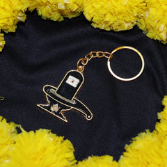 Golden Shivling keychain held in a hand