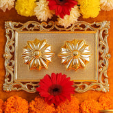A gold rectangular pooja thali with two flower-shaped containers, surrounded by red, orange, and yellow flowers.
