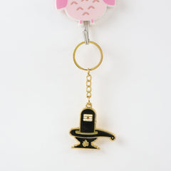 Golden Shivling keychain displayed on a white surface