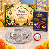 A festive gift hamper with a decorative box, a silver dish with two containers, and a box of blueberry cheesecake wafer