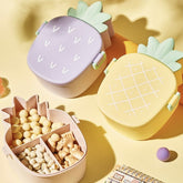 Open pineapple bento box with fork and spoon, showing food compartments