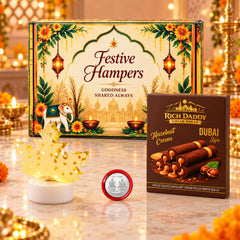 A festive gift hamper with a decorative box, a gold maple leaf lamp, and a box of hazelnut wafer rolls.
