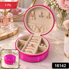 Open round hot pink travel jewellery case with a variety of rings, earrings, and a gold necklace inside.