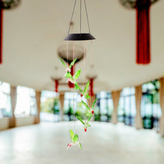 Decorative solar powered hummingbird wind chime in garden