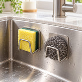 Two brushed metal sponge holders adhere to a stainless steel sink, holding a yellow sponge and a steel wool scrubber.