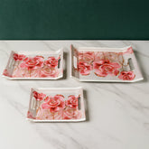 Three plastic rectangular serving trays with floral design, stacked.