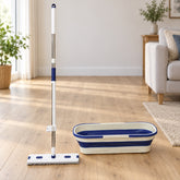 A white and blue flat mop with an extendable handle stands next to a matching collapsible bucket on a wooden floor in a