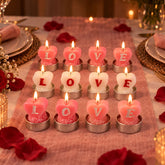 Twelve lit heart-shaped tealight candles in pink and white, arranged on a pink table runner with rose petals.
