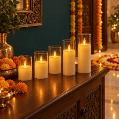 Five flameless LED candles in clear plastic sleeves illuminate a dark wooden console table decorated with a golden vase and