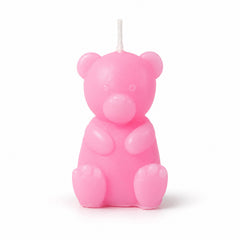 A pink teddy bear shaped candle with an unlit wick stands upright on a plain white background.