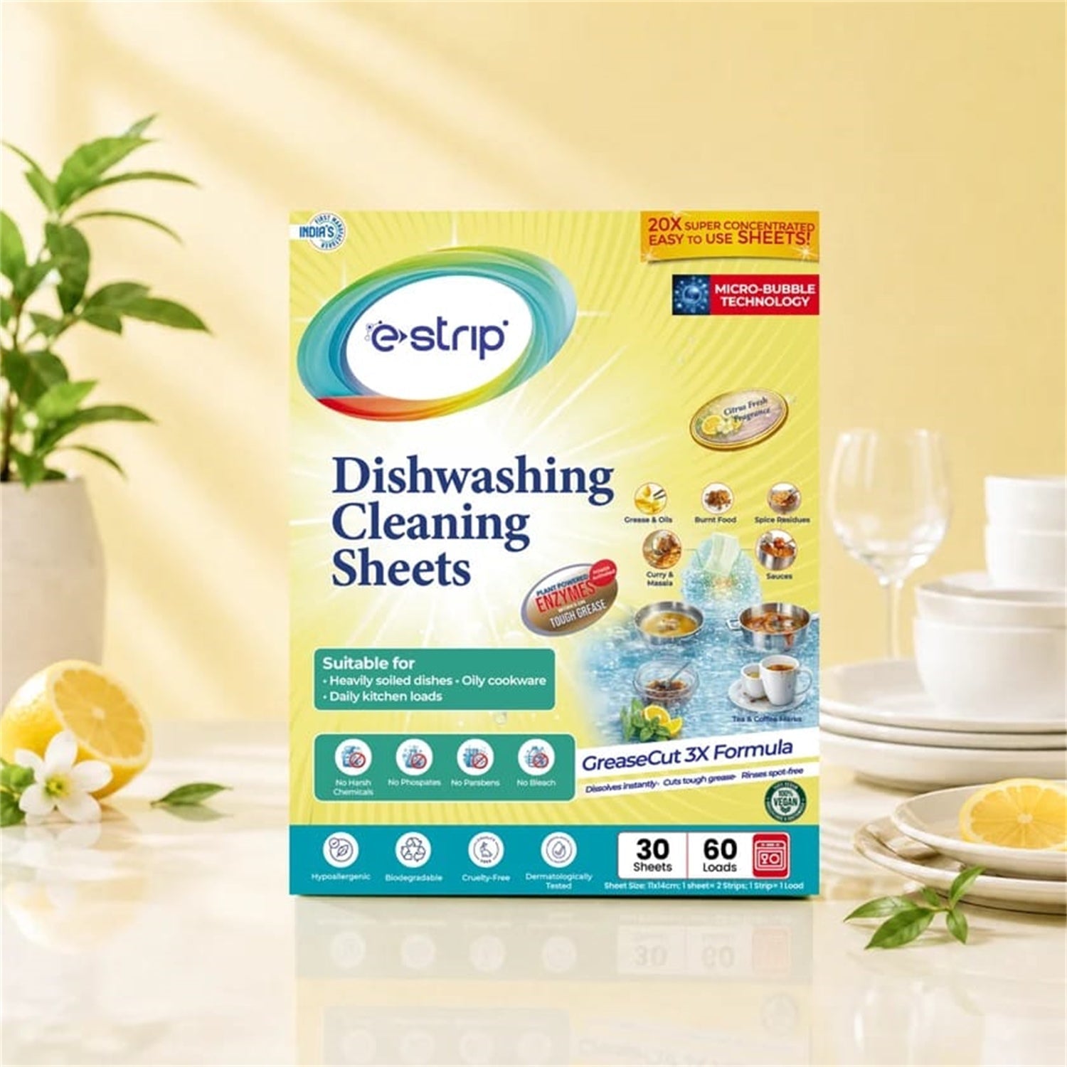 A box of e-strip dishwashing cleaning sheets on a counter with lemons, white flowers, and dishware.