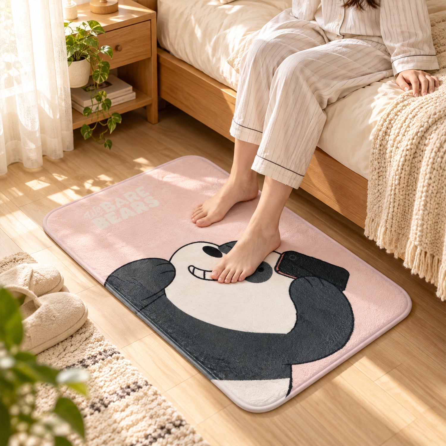 A person's bare feet step onto a pink rectangular mat featuring a cartoon panda taking a selfie in a bedroom setting.
