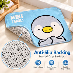 A light blue bath mat with a penguin design is partially lifted to reveal its anti-slip dotted grip surface.