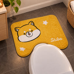 A yellow U-shaped toilet mat with a cartoon Shiba Inu face and white stars, placed on a grey tiled bathroom floor.