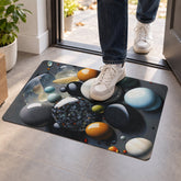 A person's feet in white sneakers stepping onto a dark grey mat with a colorful pebble design.