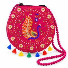 A fuchsia round purse with a beaded strap, detailed peacock embroidery, and bright tassels on a white background.