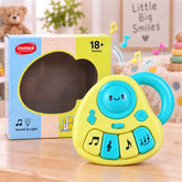 Yellow and blue musical toy with four keys and a handle, next to its packaging on a wooden surface.
