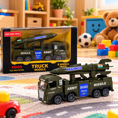 A green toy army truck with a missile launcher on its back sits on a colorful rug next to its packaging.