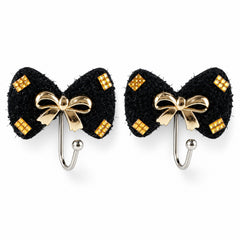 A pair of black bow-shaped hooks with gold-tone accents and a central gold bow, presented on a clean white surface.