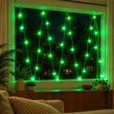 Bright green LED string lights illuminate a window at night, creating a festive glow in the room.