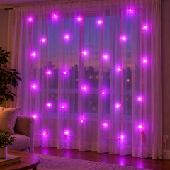 Pink LED curtain lights hang against a window, casting a vibrant purple hue over a living room couch.