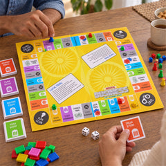 Two people's hands interact with the yellow Indian Business game board, colorful pieces, and dice on a wooden surface.