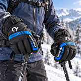 A person wearing black and blue winter gloves holding ski poles in a snowy mountain landscape.