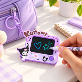 A hand draws a blue heart and green star on a purple Kuromi LCD writing tablet keychain. The tablet is attached to a light