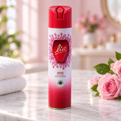 Red and white aerosol can with pink rose design, standing on a marble surface next to white towels and pink flowers.
