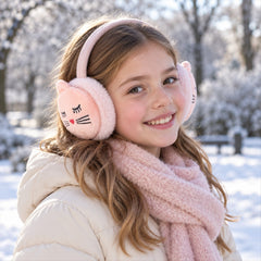 A young girl with long brown hair smiles, wearing pink cat-face earmuffs and a matching scarf in a snowy park.
