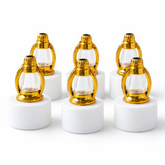 Six unlit miniature lanterns with gold tops and clear glass on white bases are arranged in two rows on a plain white