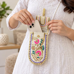 A person in a white dress places a white smartphone into an open embroidered mobile pouch.