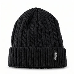 A black cable knit beanie with a textured crown and ribbed folded cuff, featuring a rectangular brand tag.
