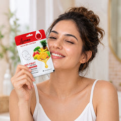 A smiling woman with brown hair holds a white and red facial sheet mask package with fruit designs to her cheek.