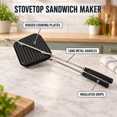 Black stovetop sandwich maker with ridged cooking plates, long metal handles, and insulated black grips on a countertop.