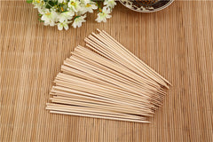 Hand holding a natural bamboo skewer with perfectly grilled meat