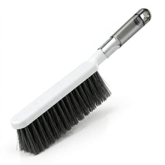 The white and gray cleaning brush with dark bristles is angled on a clean white background.