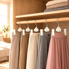 Six pairs of pants and a skirt hang neatly on white clip hangers in a light wooden wardrobe.