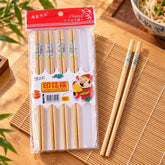 Ten pairs of natural bamboo chopsticks in clear packaging, with one pair resting beside the pack on a mat.